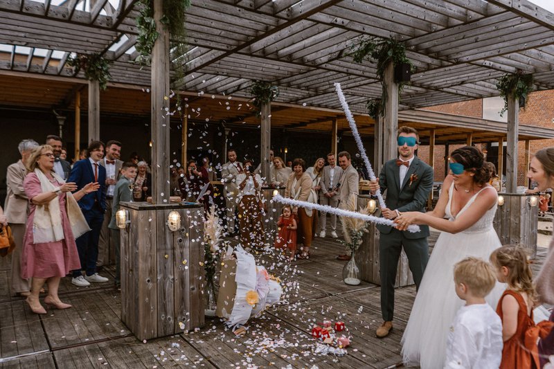 Inez%20en%20Sander%20slaan%20op%20de%20pi%F1ata%20in%20de%20vorm%20van%20een%20bruidstaart%20-%20House%20of%20Weddings