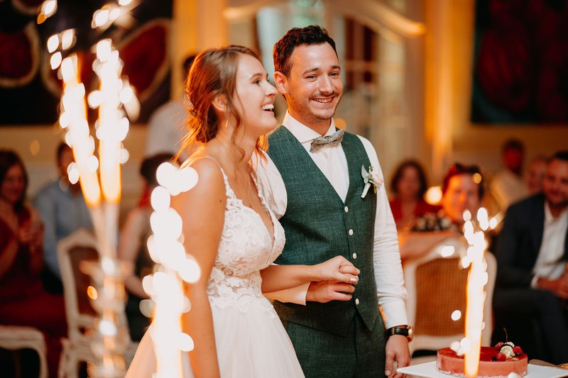 Joyce%20en%20Wannes%20snijden%20hun%20taart%20aan%20omringd%20door%20vuurwerkstokjes%20-%20House%20of%20Weddings